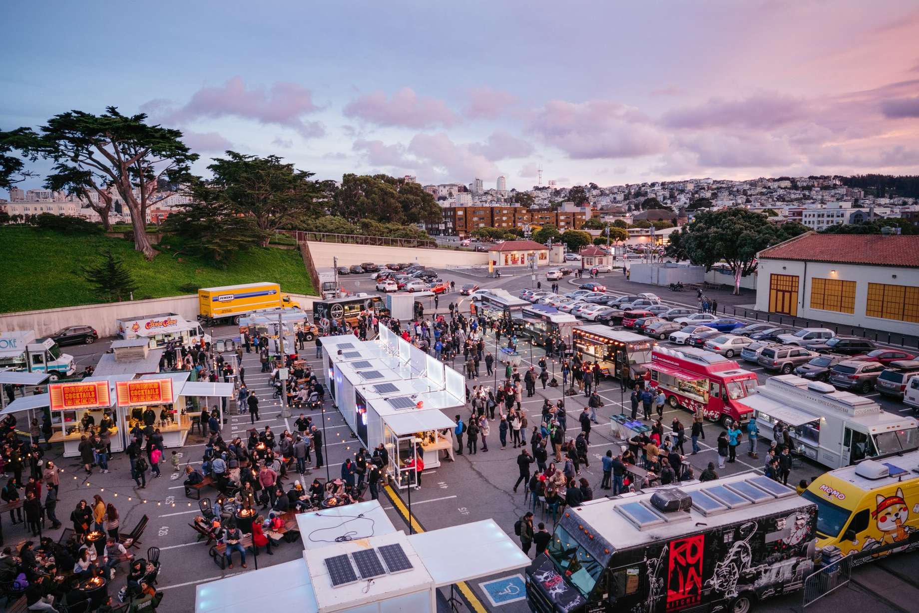 food trucks serving in San Francisco neighborhood parking lot during event at dusk